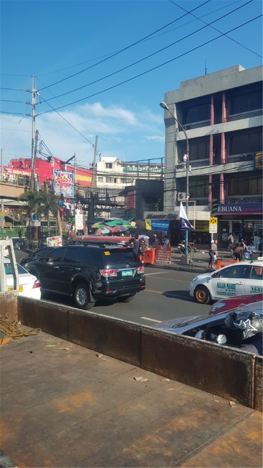 검은색 차량 너머 필리핀의 대중교통수단인 지프니에 사람들이 매달려 있는 모습. 